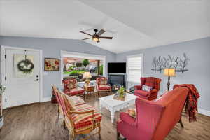 Living room featuring lofted ceiling, ceiling fan, baseboards, and wood finished floors