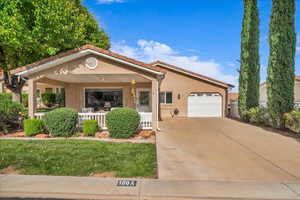 View of front of property with covered porch, an attached garage, driveway, and stucco siding
