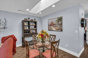 Dining space with a skylight, wood finished floors, baseboards, and recessed lighting