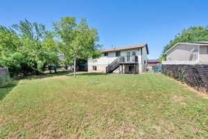 Rear view of property featuring stairs and a fenced backyard