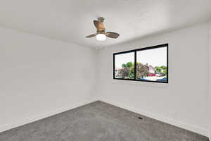 Spare room featuring dark colored carpet and ceiling fan