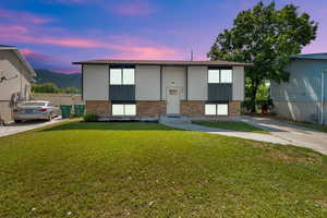 Raised ranch with brick siding, a front lawn, a mountain view, and entry steps
