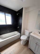 Full bath featuring toilet, wood finished floors, bathtub / shower combination, and vanity