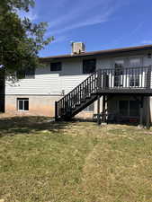 Back of property featuring stairway, a yard, a wooden deck, and cooling unit