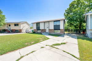 Bi-level home with a front lawn, brick siding, and driveway