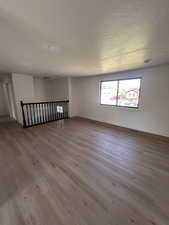 Unfurnished room featuring wood finished floors, baseboards, and a textured ceiling