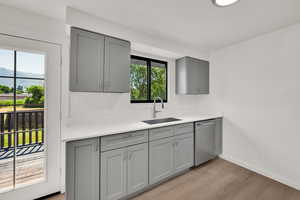 Kitchen with gray cabinetry, dishwasher, healthy amount of natural light, and light wood finished floors
