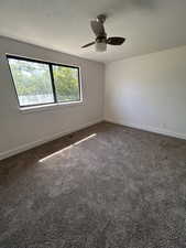 Carpeted spare room featuring baseboards and ceiling fan