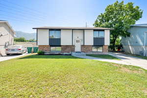 Raised ranch featuring brick siding, a front yard, a mountain view, and entry steps