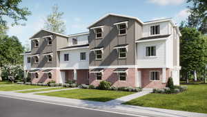 Townhome / multi-family property with board and batten siding, brick siding, and a front lawn