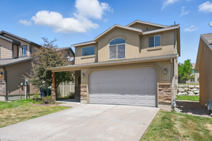 View of front of property with an attached garage, stucco siding, concrete driveway, and stone siding
