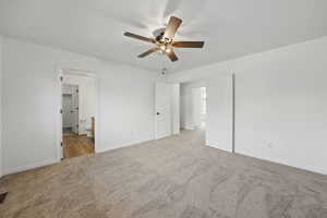 Unfurnished bedroom featuring carpet floors, baseboards, ensuite bath, and a ceiling fan