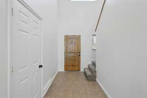 Foyer entrance featuring light tile patterned flooring, baseboards, a high ceiling, and stairs