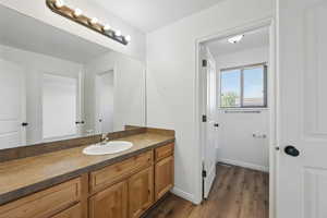 Bathroom with vanity, wood finished floors, and baseboards