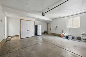 Garage with freestanding refrigerator and a garage door opener