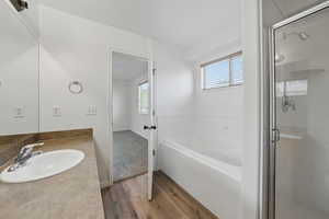 Bathroom with wood finished floors, a bath, a stall shower, and vanity