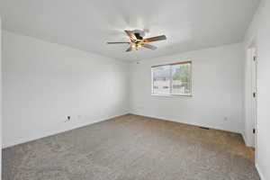 Carpeted spare room with a ceiling fan and baseboards