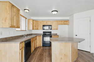 Kitchen featuring black appliances, light brown cabinetry, a sink, dark wood-style floors, and a kitchen island