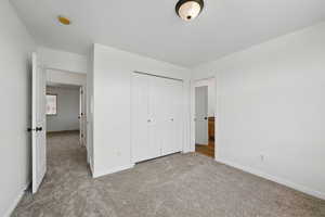 Unfurnished bedroom featuring carpet flooring, baseboards, and a closet