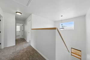 Corridor featuring an upstairs landing, carpet floors, and baseboards