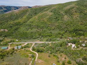 Aerial overview of property's location with a mountain backdrop and a heavily wooded area