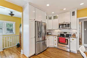 Kitchen featuring stainless steel appliances, light wood finished floors, white cabinetry, backsplash, and recessed lighting