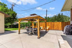 Fenced backyard with a gazebo, a patio area, outdoor dining area, and area for grilling