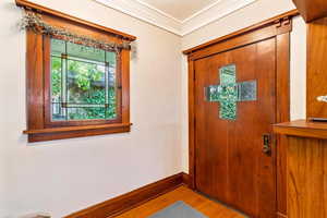 Foyer entrance with wood finished floors, baseboards, and ornamental molding
