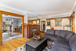 Living area featuring wood finished floors, crown molding, and a brick fireplace