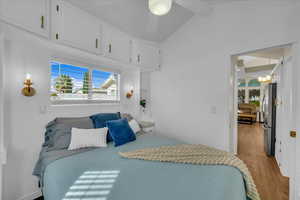 Bedroom with freestanding refrigerator, light wood-type flooring, lofted ceiling, and a chandelier