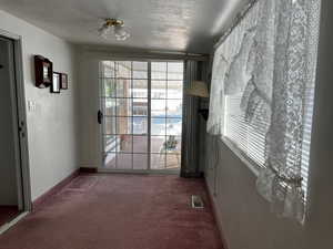 Doorway featuring carpet floors, a textured ceiling, and baseboards