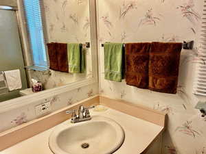Bathroom with vanity and wallpapered walls