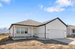 View of front of house with a garage, covered porch, driveway, and stone siding