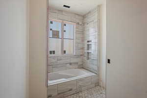 Full bath featuring tiled bath and tile patterned floors