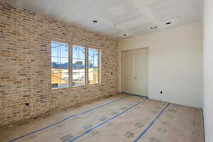 Unfurnished bedroom with brick wall and a closet