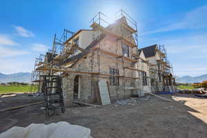 View of property exterior featuring stone siding, a mountain view, and stucco siding