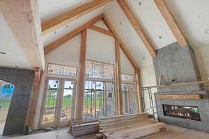 Living room featuring high vaulted ceiling, beamed ceiling, a fireplace, and french doors