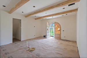 Empty room featuring arched walkways and beam ceiling