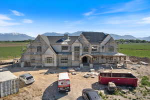 View of front of home featuring a balcony, a mountain view, a view of countryside, stone siding, and roof with shingles
