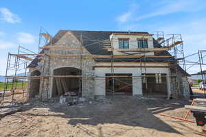 View of front of house with stone siding, a shingled roof, and stucco siding