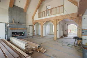 Unfurnished living room with high vaulted ceiling, a large fireplace, arched walkways, and beam ceiling