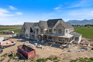 Rear view of property with stone siding, a view of countryside, a mountain view, and a shingled roof