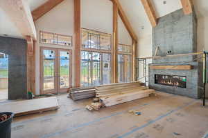 Living room with high vaulted ceiling, beamed ceiling, a large fireplace, and french doors