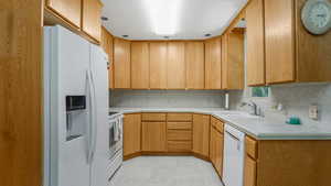 Kitchen featuring white appliances, a sink, light countertops, and backsplash