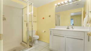 Bathroom featuring toilet, a stall shower, vanity, and tile patterned floors