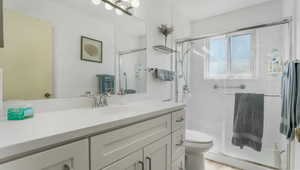 Bathroom featuring vanity, toilet, and a shower with door