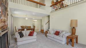 Carpeted living room featuring a chandelier, a towering ceiling, stairs, and a fireplace