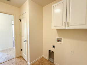 Laundry room with hookup for an electric dryer, washer hookup, cabinet space, light tile patterned floors, and baseboards