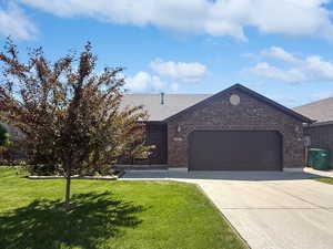 View of front of home with brick siding, a garage, concrete driveway, a front yard, and a shingled roof