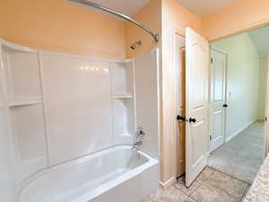Full bathroom featuring tile patterned floors, washtub / shower combination, and baseboards